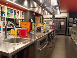 A modern kitchen with stainless steel appliances, a large sink, and colorful storage bins.