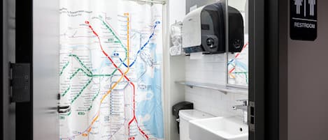 Une salle de bain avec une carte imprimée sur le rideau de douche, un lavabo et des toilettes.