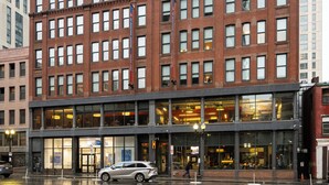 Un immeuble à plusieurs étages, doté de grandes fenêtres et d’une façade en briques.