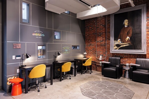 A modern workspace with desks, chairs, and a large portrait on the wall.