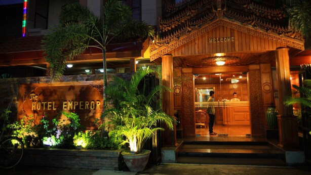 The exterior of The Hotel Emperor with a traditional architectural style, a reception desk, and a signboard. - The Hotel Emperor (Mandalay)