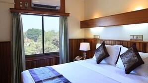 A hotel room with a large bed, a window with curtains, an air conditioning unit, a bedside lamp, and a phone on the nightstand. - The Hotel Emperor (Mandalay)