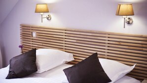 Una habitación de hotel con cabecera de madera, dos lámparas de noche y dos almohadas.