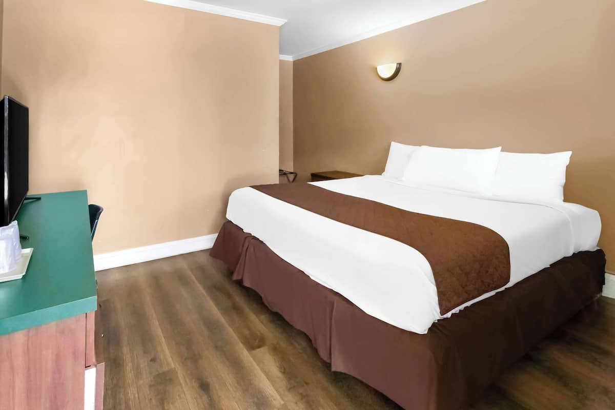 A hotel room with a bed, a desk, and a television.