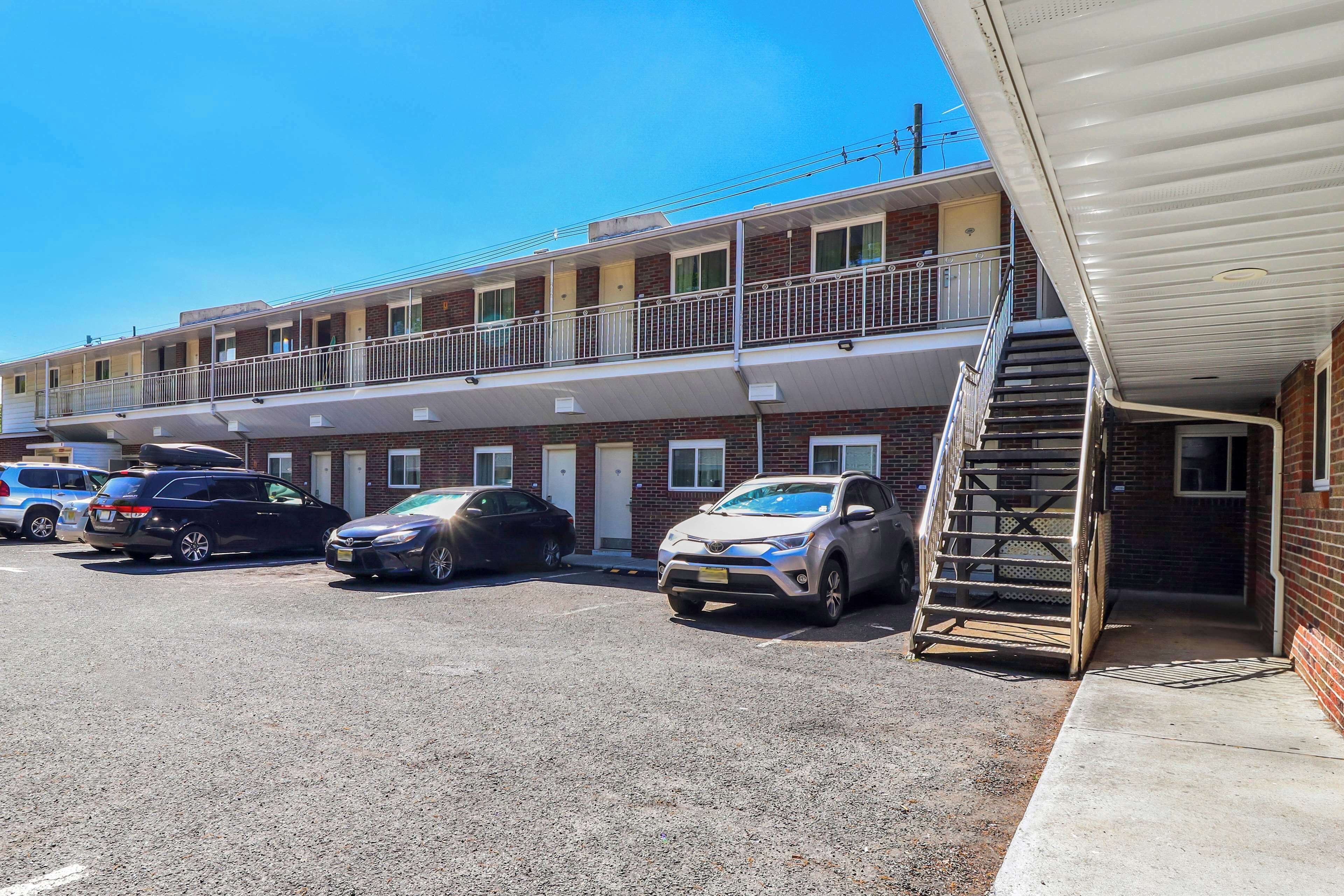 A motel with a two-story structure, a covered parking area, and a staircase leading to the entrance.