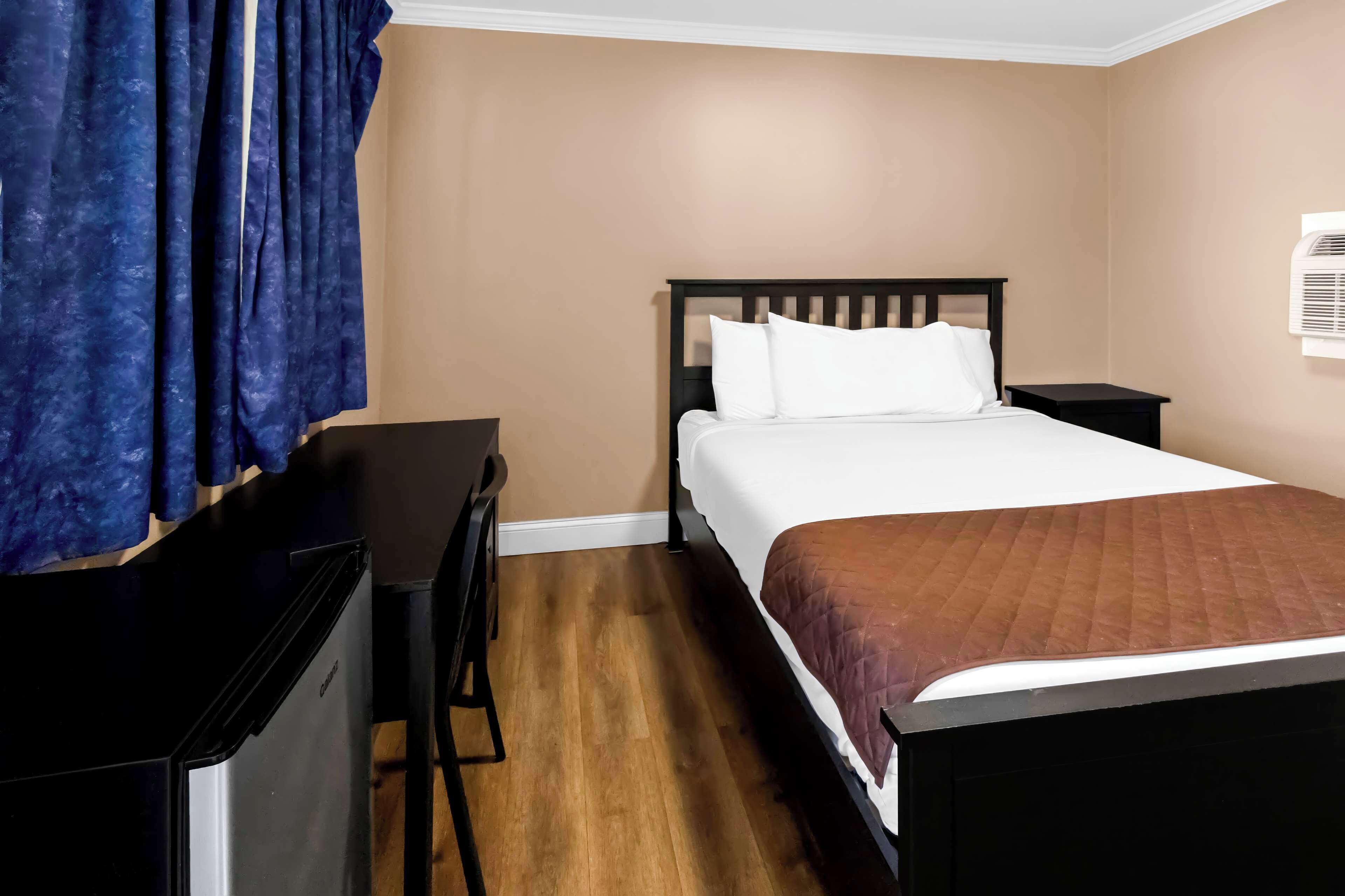 A bedroom with a bed, a desk, and a chair.