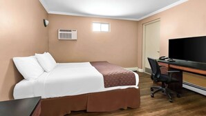 A hotel room with a bed, a desk, a chair, a television, and an air conditioning unit. - Americas Best Value Inn Avenel Woodbridge (Avenel)