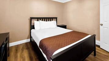 Quarto com cama, mesa de cabeceira e porta.