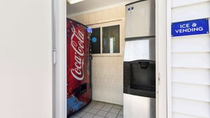 A kitchen with a Coca-Cola vending machine, a refrigerator, and an 'Ice & Vending' sign. - Americas Best Value Inn Avenel Woodbridge (Avenel)