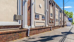 A building with a brick facade, large windows, and a blue sign indicating a location. - Americas Best Value Inn Avenel Woodbridge (Avenel)