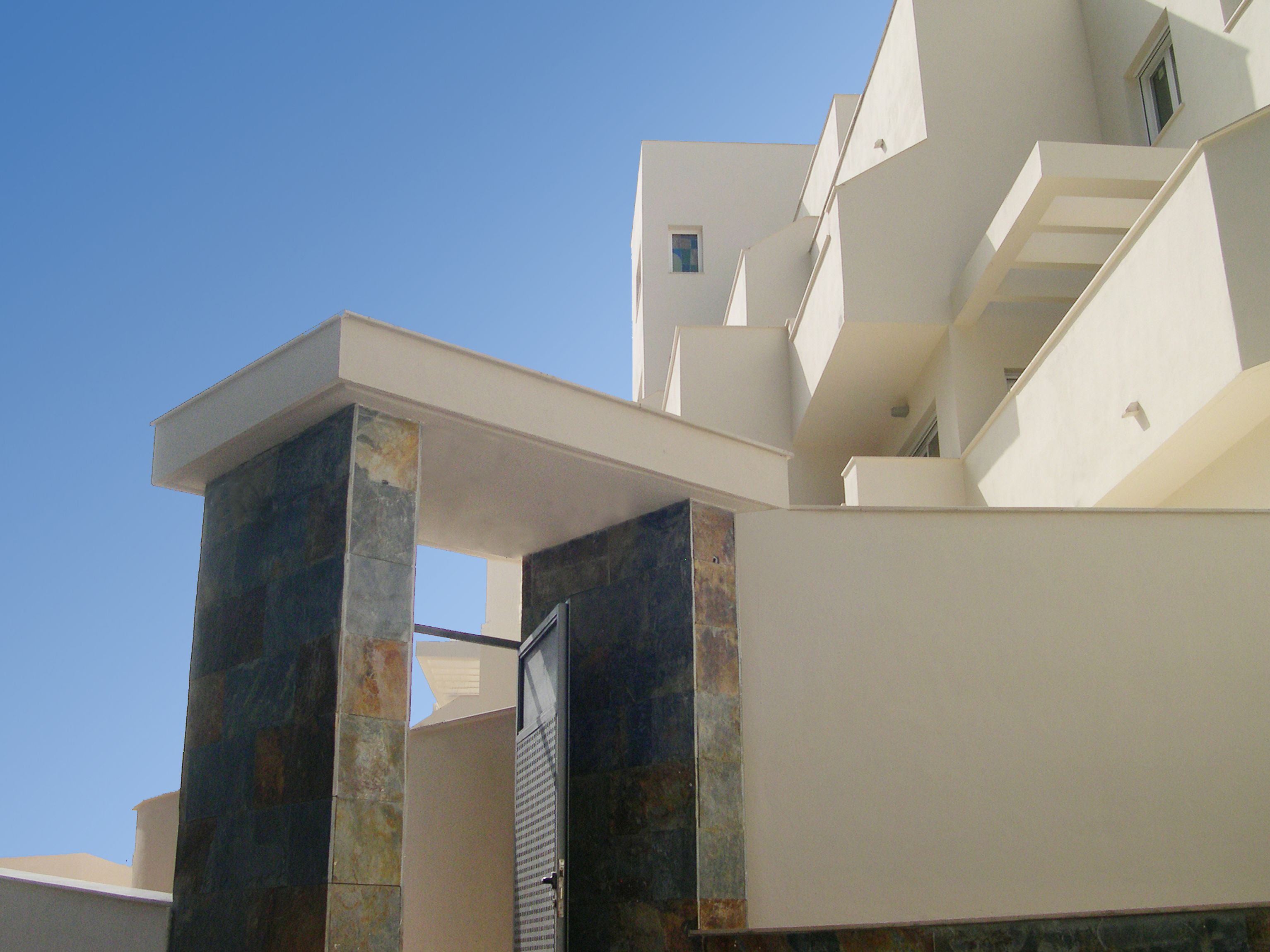 Un bâtiment moderne doté d’un toit plat, d’une grande entrée ouverte et d’une petite fenêtre à l’étage supérieur.