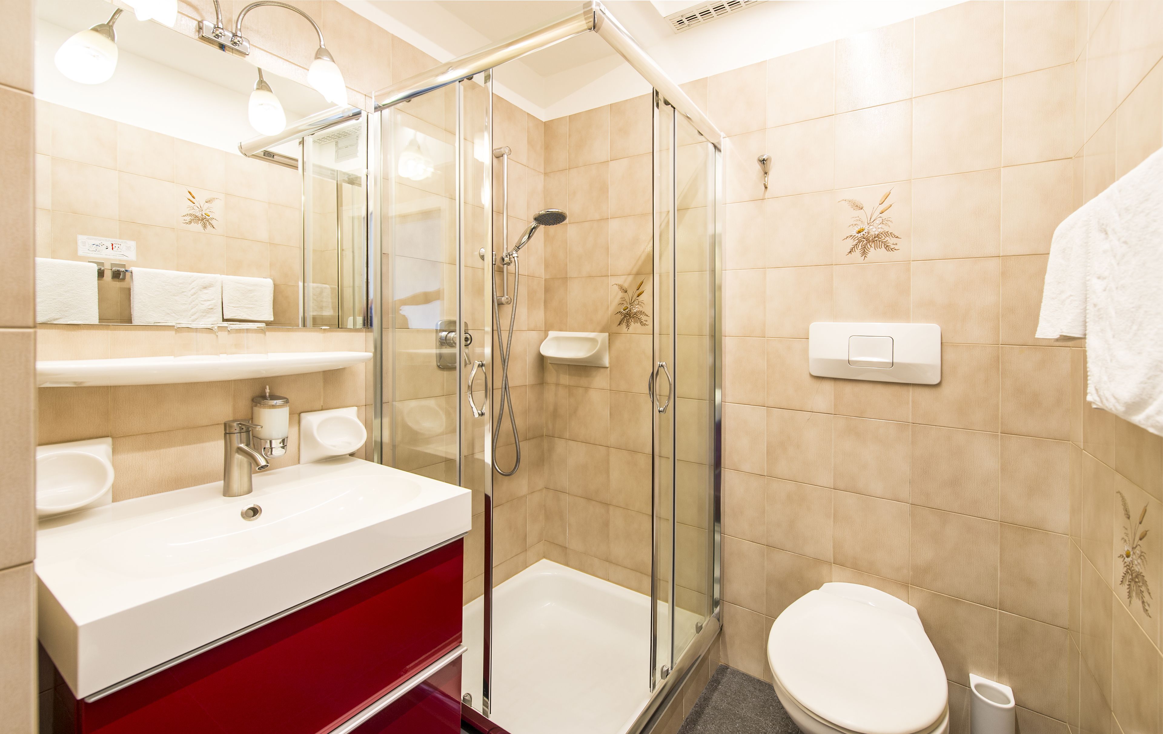 Ein modernes Badezimmer mit einer Duschkabine aus Glas, einem weißen Waschbecken und einem roten Schrank.