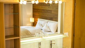 Un baño moderno con un lavabo de vidrio, un espejo sobre el lavabo y un cabecero de madera al fondo.