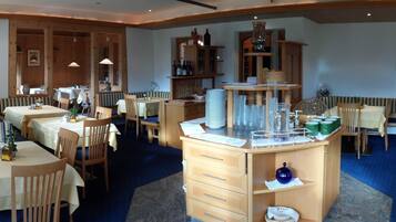 A restaurant with wooden furniture, tables, and a central counter with various items.