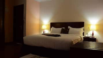 Ein Hotelzimmer mit einem großen Bett, zwei Nachttischen mit Lampen und einem Paar Hausschuhen auf dem Boden.