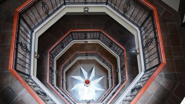 Una escalera espiral de varios niveles con barandillas octogonales y un diseño central en forma de estrella.