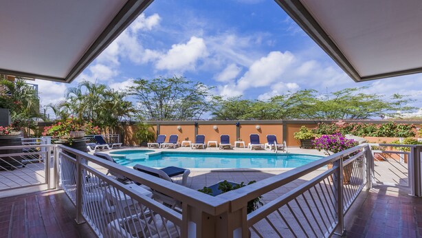 A pool area with lounge chairs and a view of the sky. - King David Suites (Noord)