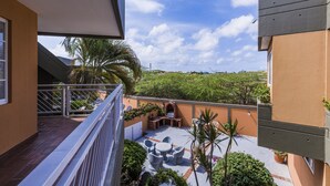 A balcony with a patio area, outdoor furniture, and a view of greenery and hills. - King David Suites (Noord)