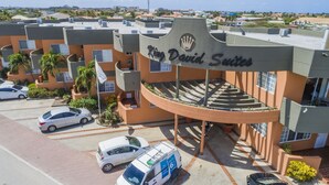A hotel with a curved entrance, a flag, and a sign reading "King David Suites". - King David Suites (Noord)