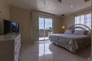 A bedroom with a bed, a television on a dresser, and a balcony with a view. - King David Suites (Noord)