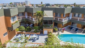 A multi-story hotel with outdoor swimming pool, balconies, and potted plants. - King David Suites (Noord)