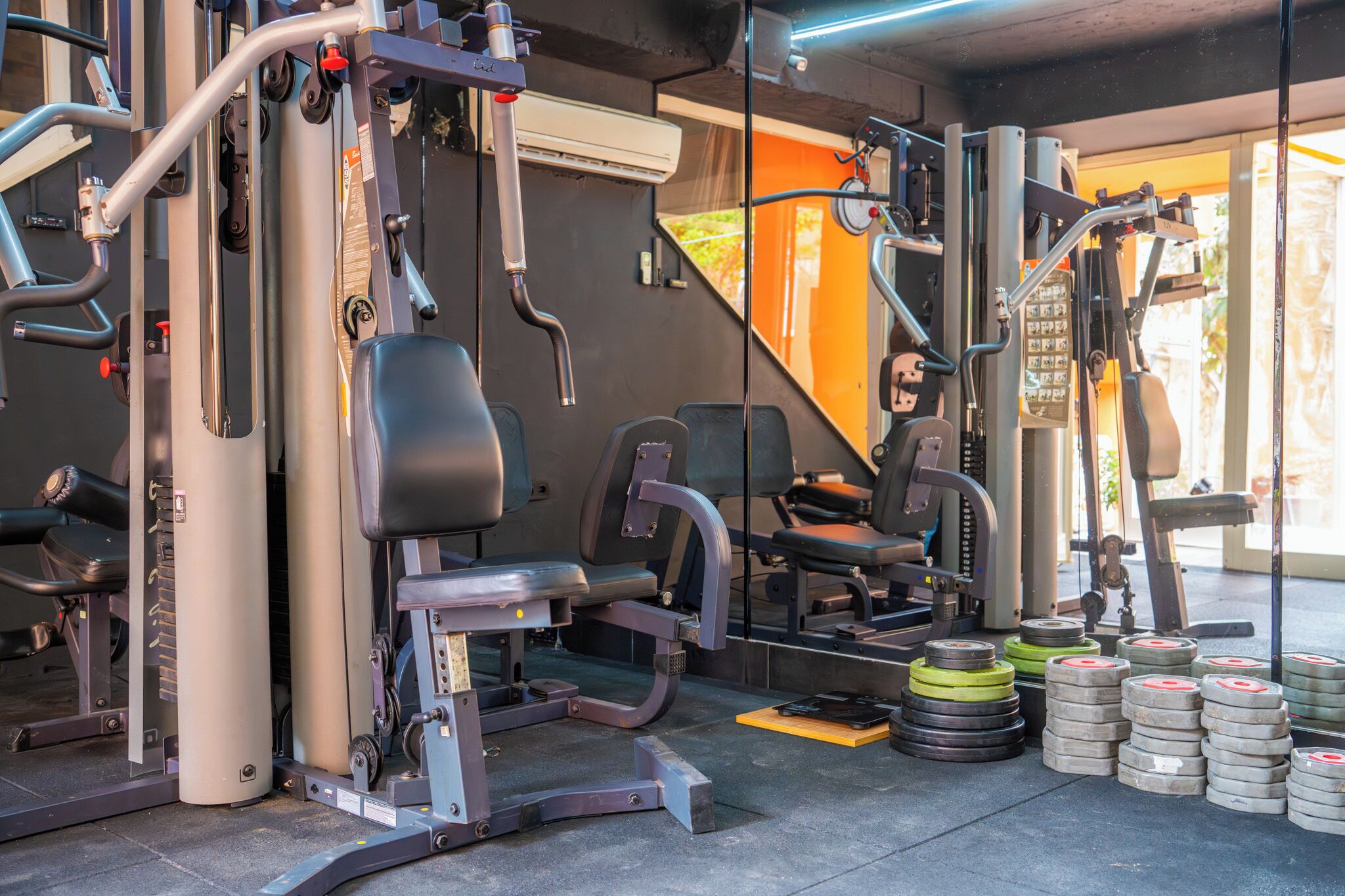 A gym with exercise equipment, weight stacks, and a bench.