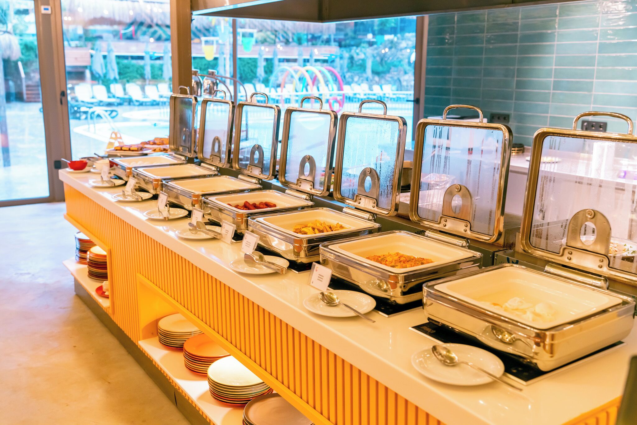 Ein Buffet mit mehreren Selbstbedienungsstationen, jede mit einer transparenten Glasschutzhaube und Beschriftung der Speisen.