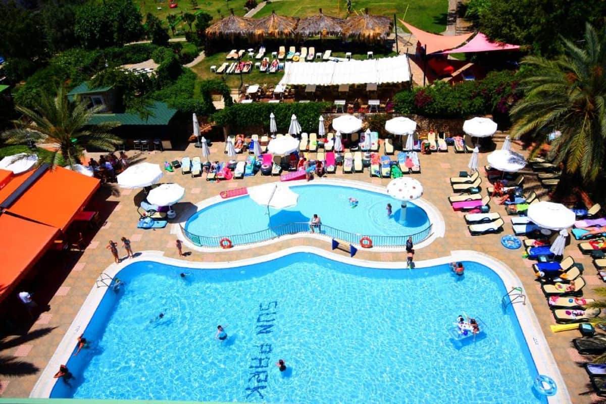 A large swimming pool with multiple lanes, surrounded by sun loungers and umbrellas.
