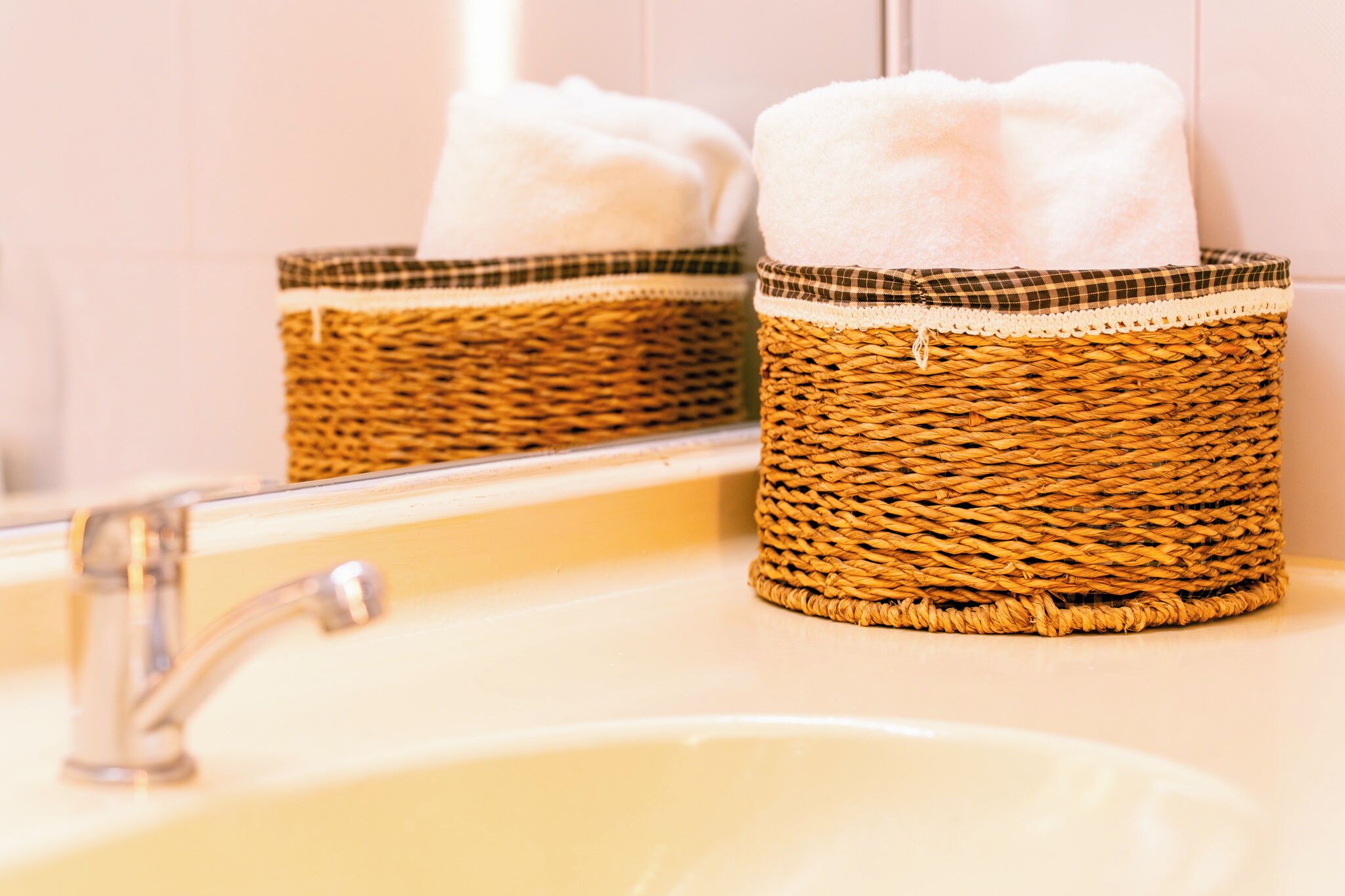 Ein Badezimmer mit Waschbecken, Spiegel und zwei gewebten Körben mit weißen Handtüchern.