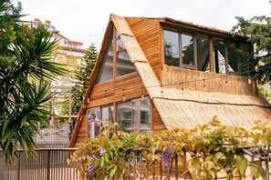 Une maison moderne en bois, dotée de grandes fenêtres et d’un toit de chaume.