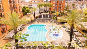 Una piscina con lettini, palme e uno scivolo d'acqua.