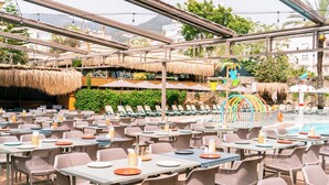 An outdoor dining area with tables and chairs, a pool, and thatched umbrellas. - Calimera Sunpark Alanya (Alanya)