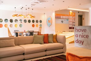 A modern interior with a sofa, a 'have a nice day' sign, a wall with circular mirrors, and a wooden table with chairs. - Calimera Sunpark Alanya (Alanya)