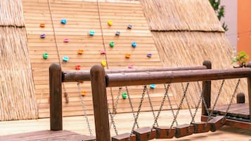 Ein Holzschaukelstuhl mit einem strohgedeckten Bauwerk im Hintergrund.