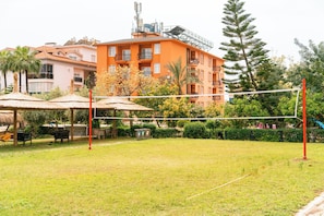 A grassy outdoor area with a volleyball net, umbrellas, and outdoor seating. - Calimera Sunpark Alanya (Alanya)