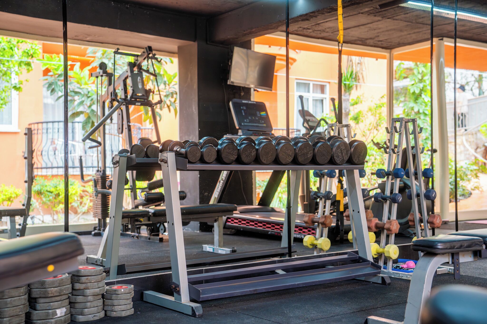 A gym with various exercise equipment, including dumbbells and weight plates.