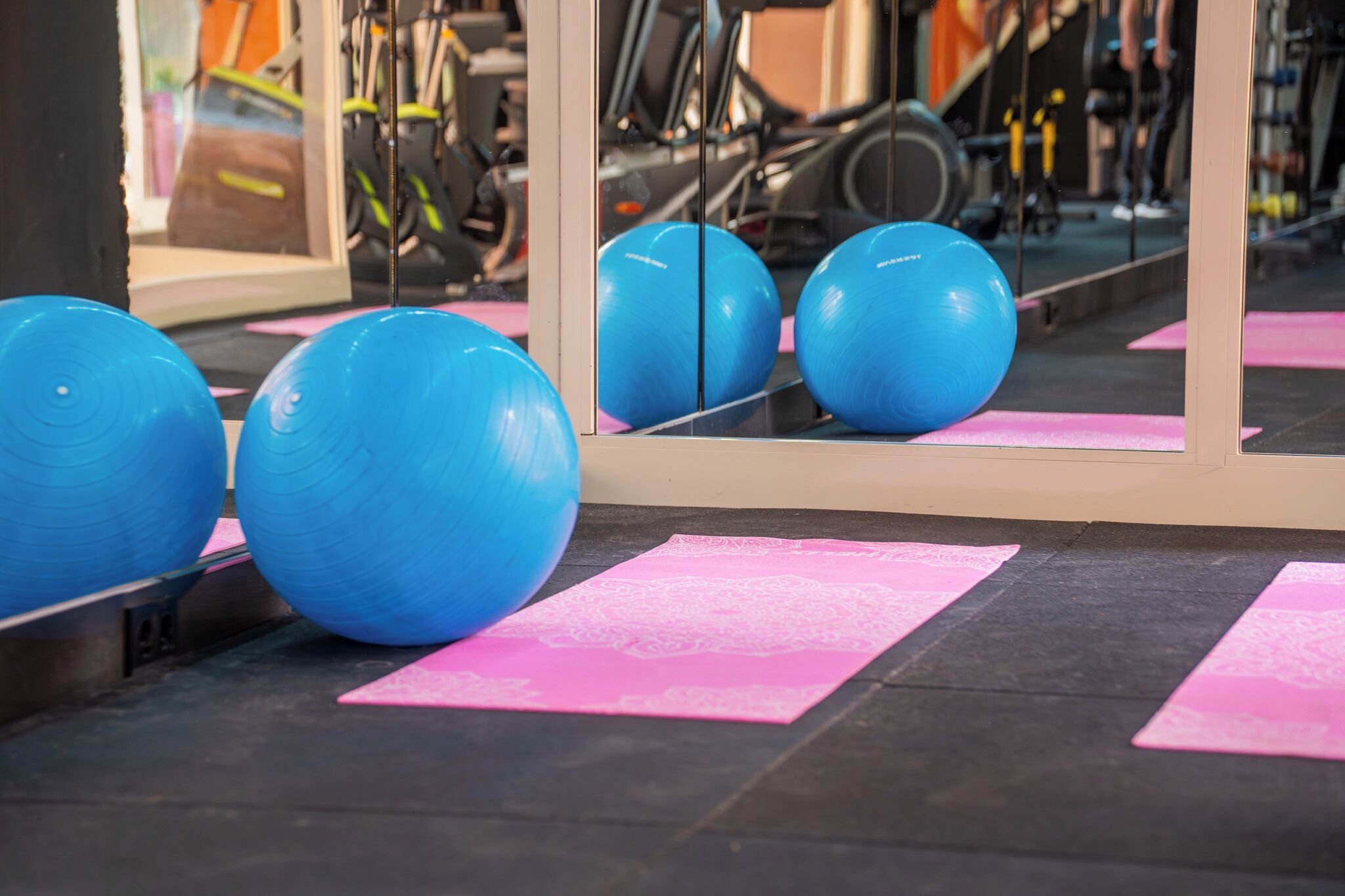 A gym with exercise equipment and pink mats on the floor.