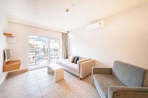 A modern living room with a sofa, a bench, and a TV. - Calimera Sunpark Alanya (Alanya)