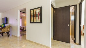 Un couloir avec une porte sombre, une œuvre d’art accrochée au mur et un coin repas avec des meubles en osier.