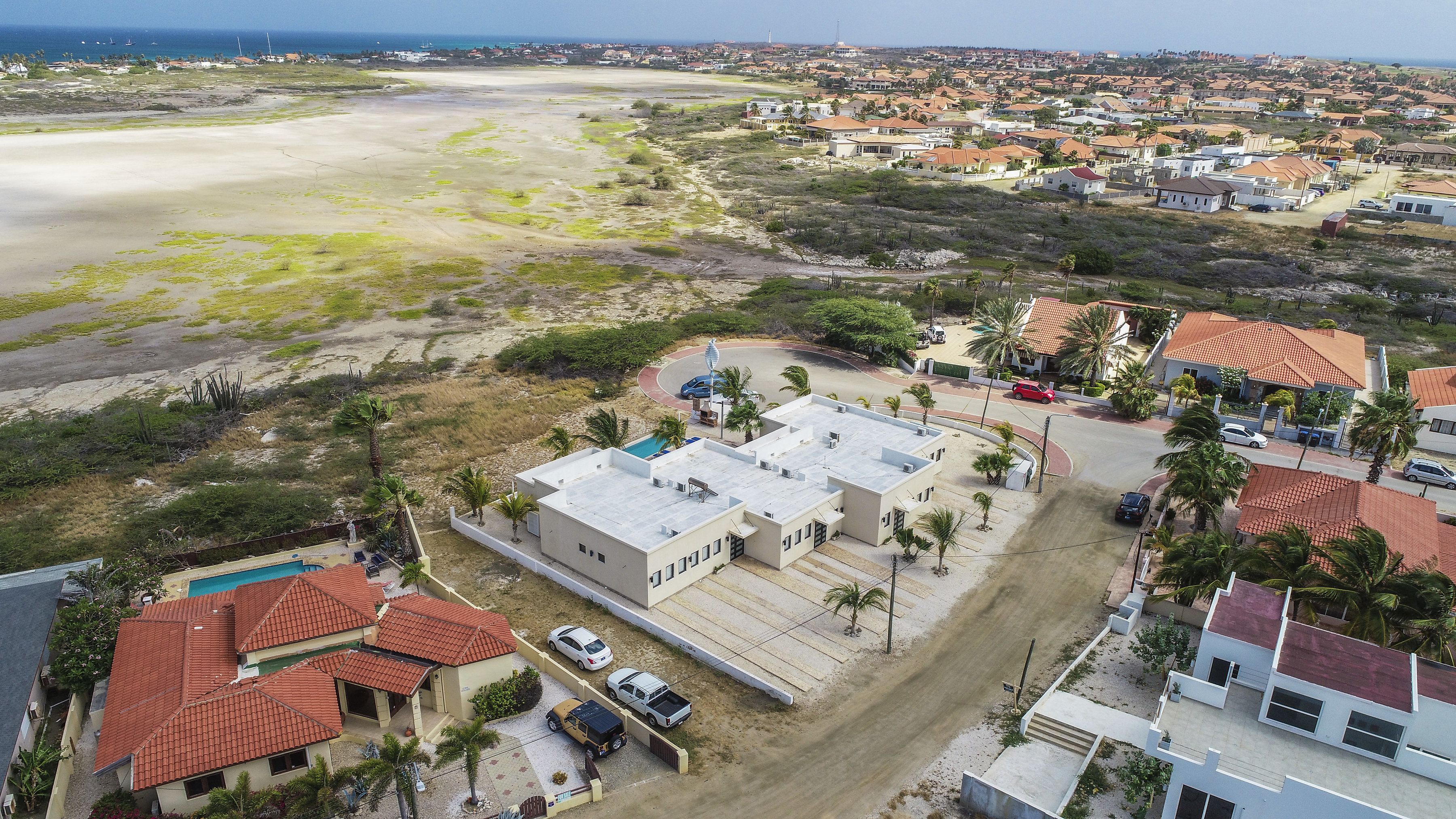A coastal residential area with houses, a beach, and a swimming pool.