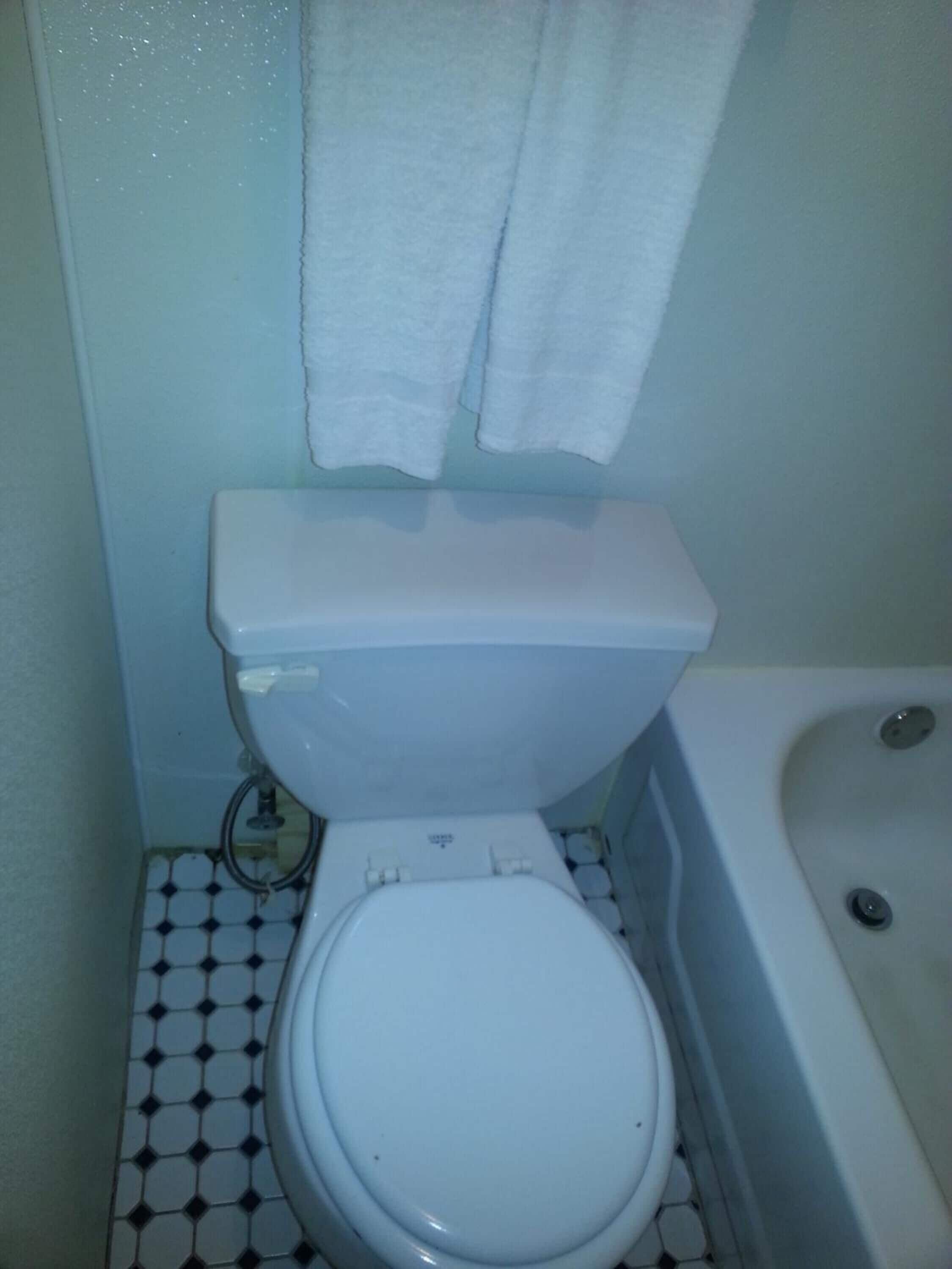 A small bathroom with a toilet, a bathtub, and a tiled floor.