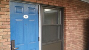 A blue door with the number 11, a window, and a brick wall. - Americana Motel (Avenel)