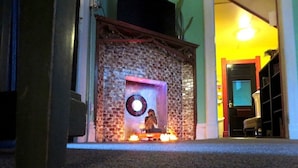 A room with a brick wall, a small statue, and a circular object on a shelf.