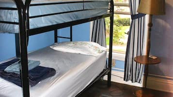 Une chambre avec un lit superposé, une fenêtre, des rideaux, une lampe et un tapis.