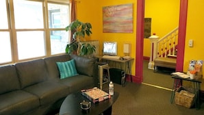 A living room with a sofa, coffee table, and a TV. There is a staircase leading to another room.