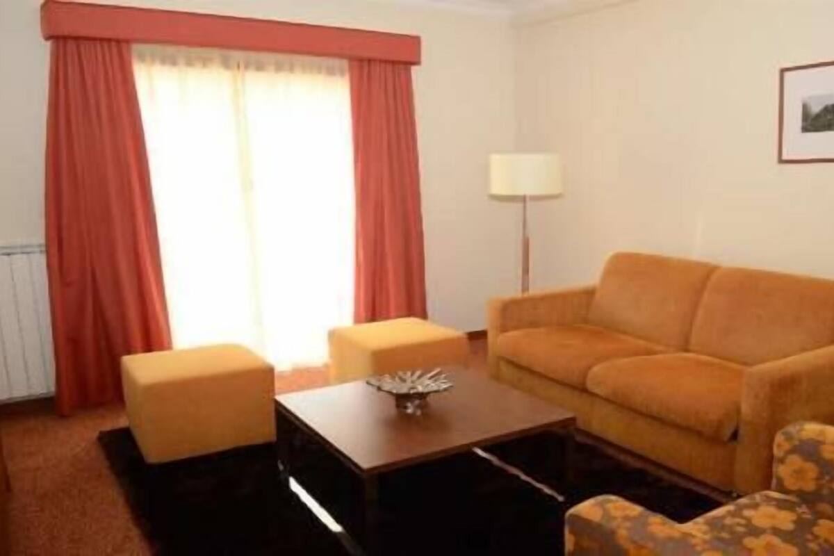 A living room with a sofa, two armchairs, a coffee table, and a lamp.