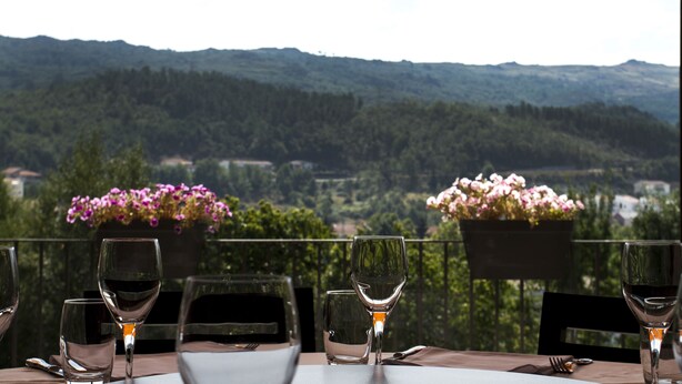 Une table avec des verres à vin vides et une vue sur un paysage montagneux.