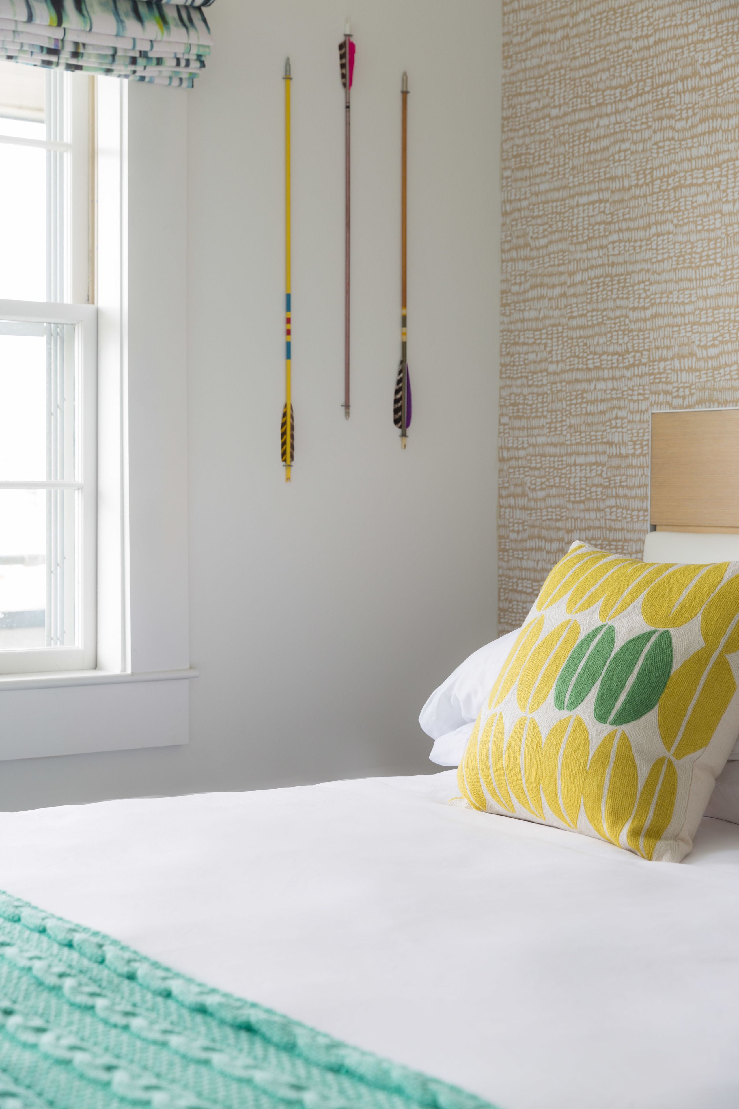 A bedroom with a bed, pillows, a window, and wall decorations.