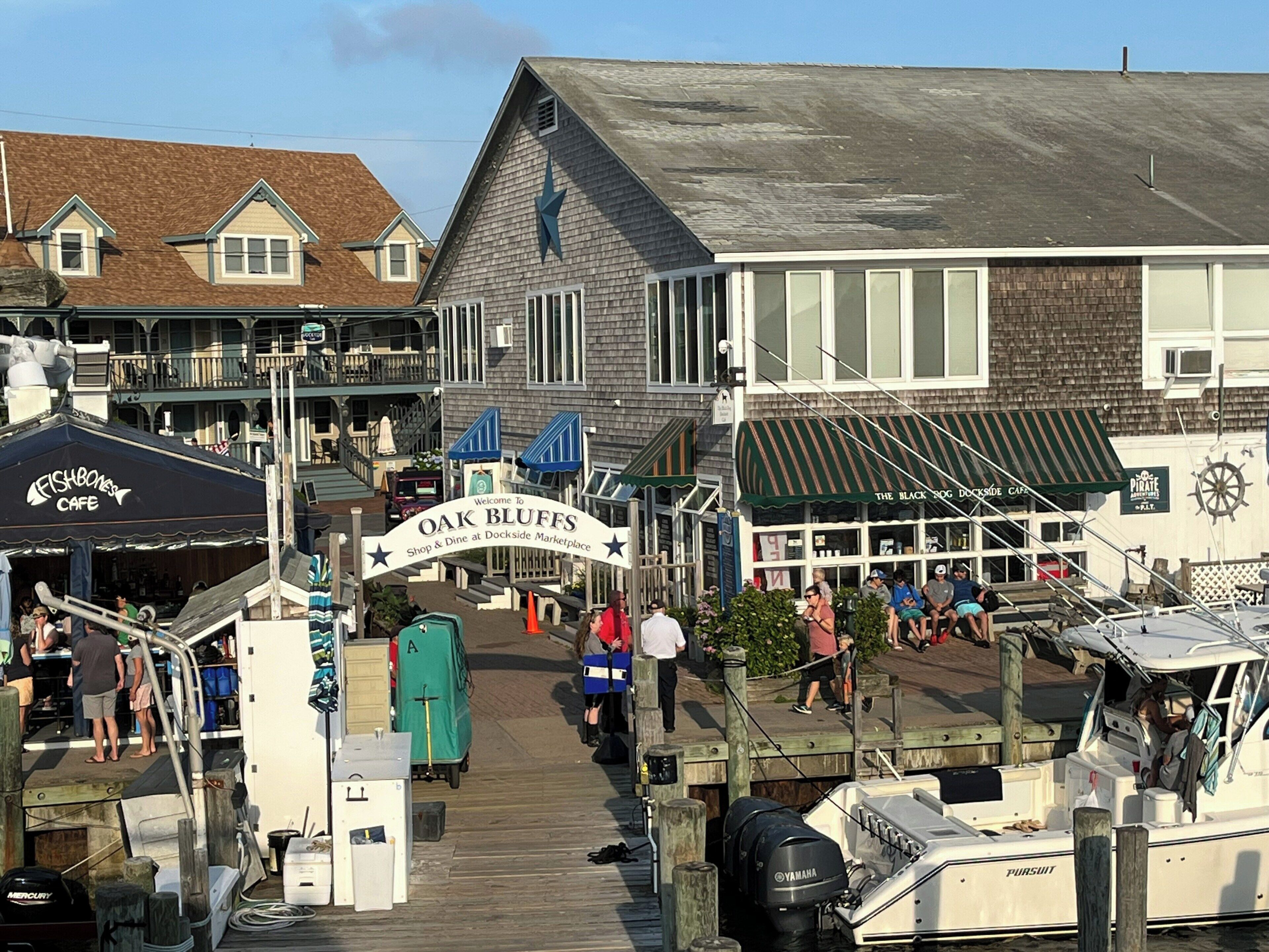 A waterfront dock area with a sign for 'Oak Bluffs Shop & Dine at Dockside Marketplace.'