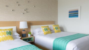 A hotel room with two beds, a headboard, a nightstand with a lamp, and a framed picture on the wall.
